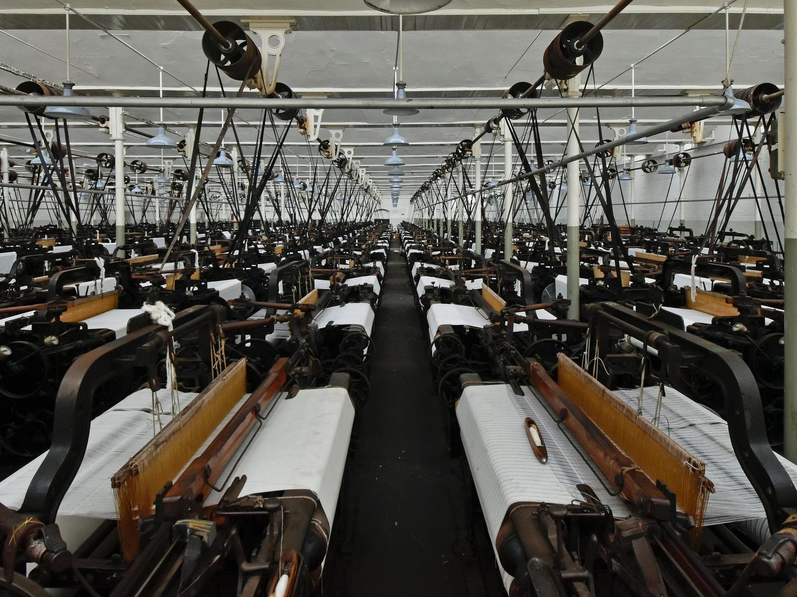 Weaving shed with rows of looms producing white fabric